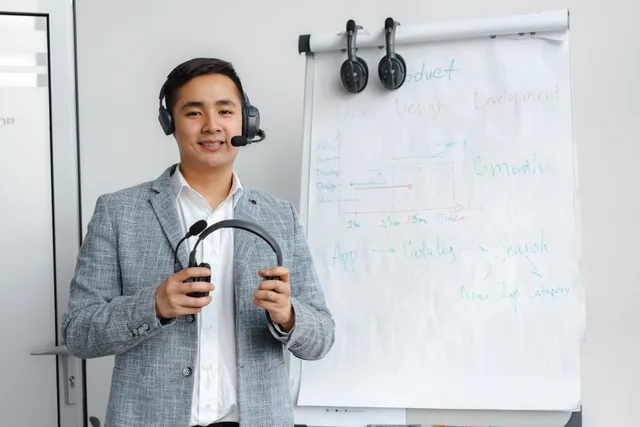 Friendly call center agent wearing headphones in an office setting with a flip chart presentation. Bringing support and customer success insights into training