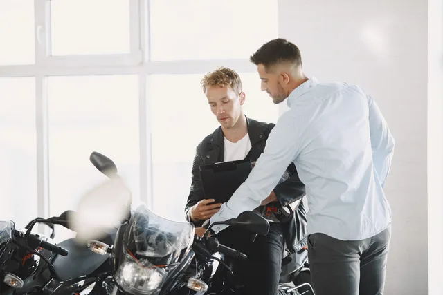 Two adults discussing motorcycle purchase inside dealership. Defining what a new representative should demonstrate