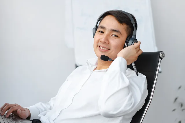 Asian call center agent sitting at desk with headset, smiling. Giving feedback from observed conversation evidence