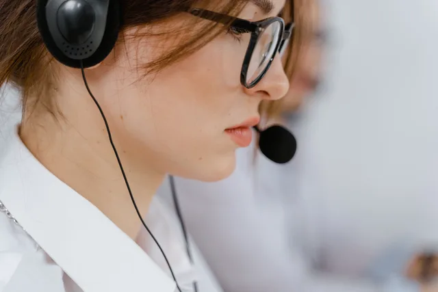 A young woman with glasses and headset intensely focused on her work in an office environment. Giving representatives time to apply a newly learned skill