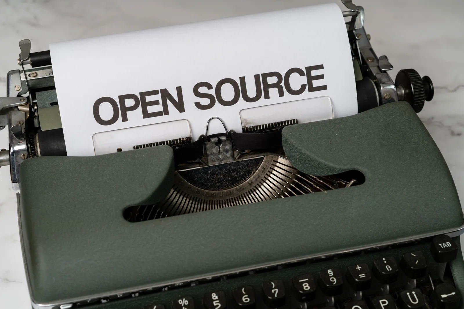 Close-up of a vintage typewriter with 'Open Source' typed on paper, conveying creativity.